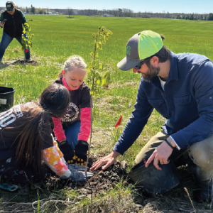 TILT Stewardship Director Ken Nims assists a few volunteers with their tree planting on Arbor Day. © Bridgett McCann